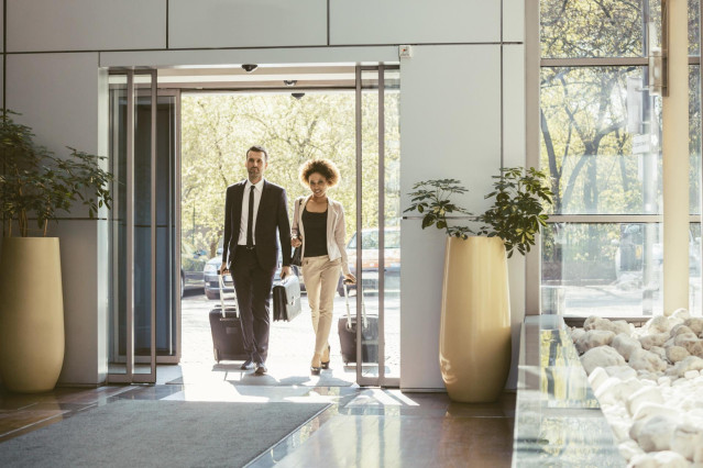 Archivo - Viajeros de negocios entrando en un hotel con sus maletas.