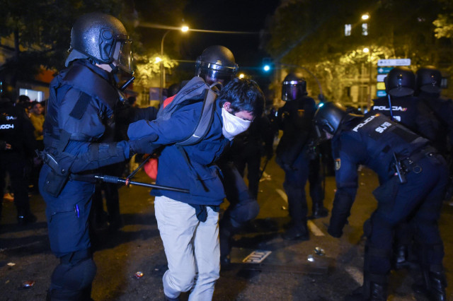 Un joven embozado es detenido por varios agentes de policía, durante una manifestación contra la amnistía frente a la sede del PSOE en Ferraz, a 18 de noviembre de 2023, en Madrid (España).