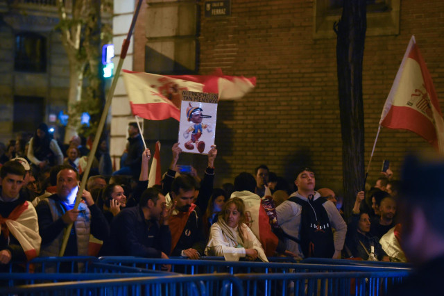 Decenas de manifestantes con banderas y carteles tras las vallas de seguridad y frente a varios agentes de policía, durante una manifestación contra la amnistía frente a la sede del PSOE en Ferraz