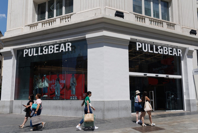 Archivo - Varias personas pasan por delante de una tienda de Pull&Bear del grupo textil Inditex, en Madrid (España).