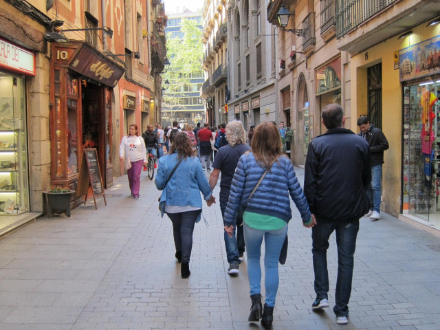 Archivo - Personas caminando por una calle comercial
