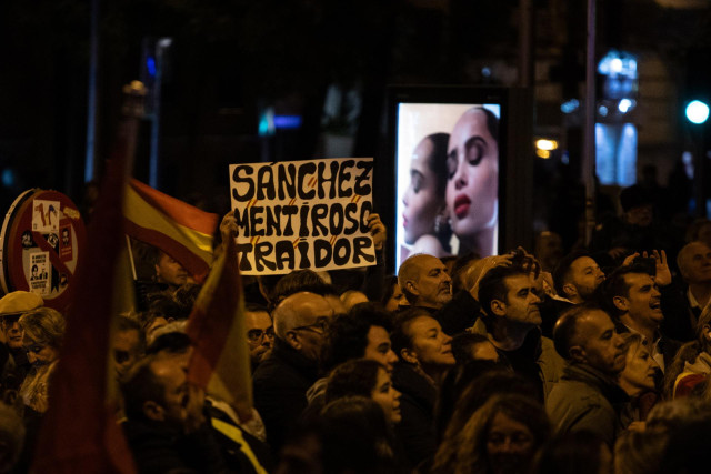 Decenas de personas portando banderas y carteles, durante una protesta contra la amnistía, frente a la sede del PSOE, a 11 de noviembre de 2023, en Madrid (España).