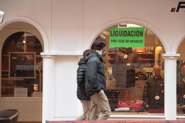 Archivo - Dos personas pasan por delante de un establecimiento en liquidación