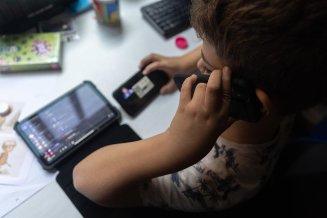 Archivo - Un niño usa el teléfono móvil y una tablet, a 18 de octubre de 2023, en Madrid (España). Según la Vanguardia, en España se estima que el 21% de los adolescentes es adicto a la red y casi la mitad reconoce que tiene 
