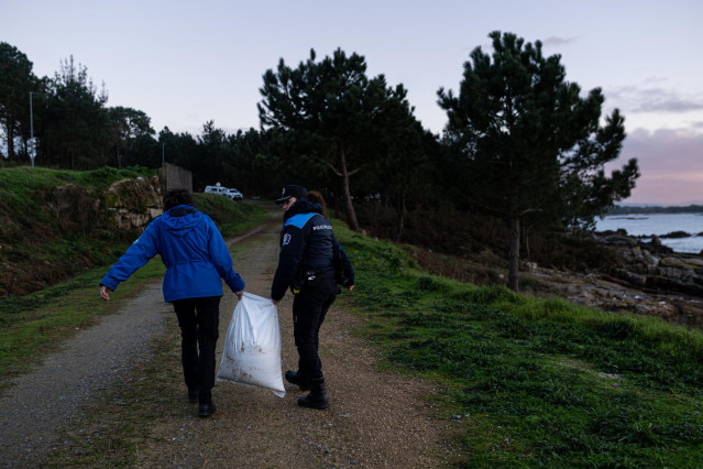 Un agente de la Policía Local y una guarda costas hacen una recogida de pellets de la arena, en la Illa de Arousa, a 4 de enero de 2024, en Pontevedra, Galicia (España).Grandes cantidades de pellets de plásticos llevan apareciendo, desde el 13 de diciembr
