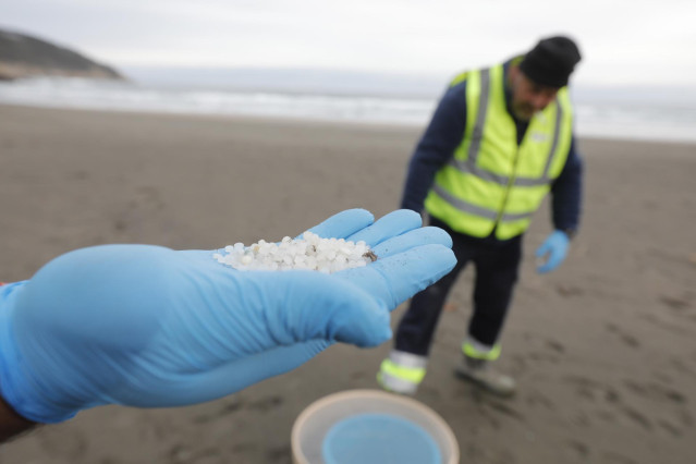 Archivo - Un operario de TRAGSA coge con la mano pellets de plástico, en la playa Otur, a 9 de enero de 2024, en Valdés, Asturias (España).