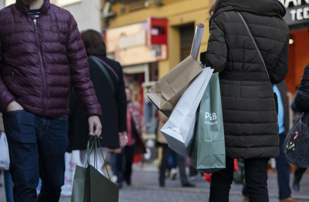 Archivo - Varias personas con bolsas de la compra en una calle céntrica