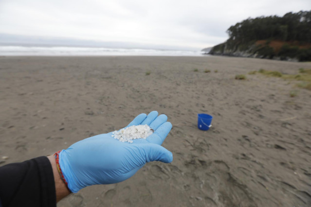 Archivo - Un operario coge con la mano pellets de plástico, en la playa Otur,