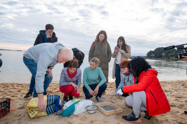 Varias personas observan las herramientas para quitar los pellets, durante una visita a la Praia da Corna, a 12 de enero de 2024, en Ribeira, A Coruña, Galicia (España). La vicepresidenta segunda y ministra de Trabajo ha visitado hoy Praia da Corna para c
