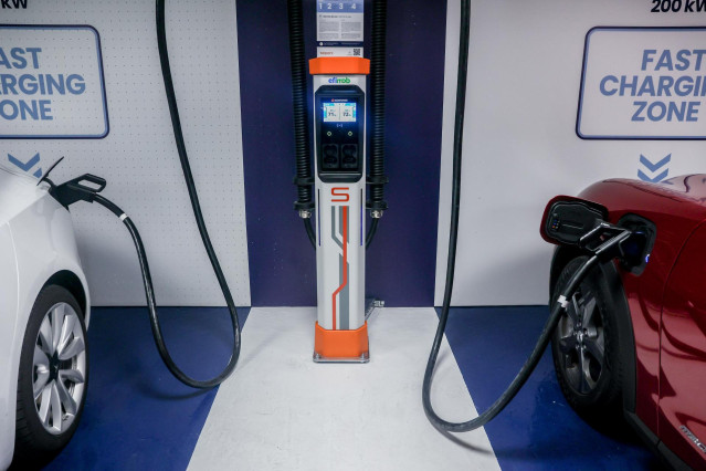 Archivo - Dos coches eléctricos se cargan en una estación de carga durante la séptima edición de la Feria del Vehículo Eléctrico.