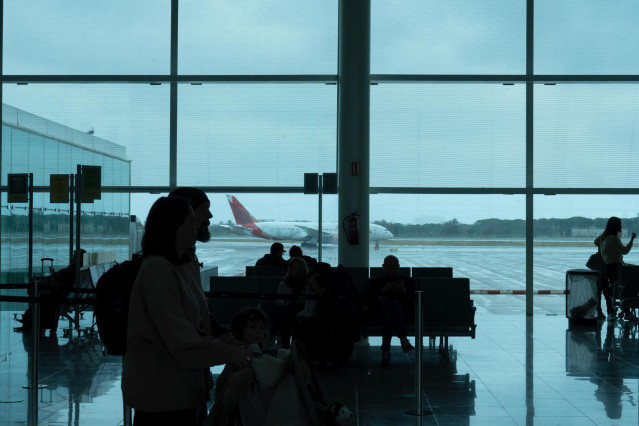 Varias personas esperan sentadas frente a un avión aparcado en la pista del aeropuerto de El Prat, a 19 de enero de 2023, en el Prat de Llobregat, Barcelona, Catalunya (España)