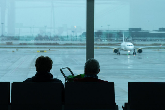Archivo - Dos personas esperan sentadas frente a un avión aparcado en la pista del aeropuerto de El Prat, a 19 de enero de 2023, en el Prat de Llobregat, Barcelona, Catalunya (España).
