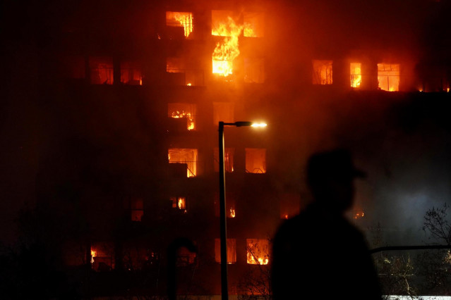 Un agente observa el edificio en llamas, en el barrio de Campanar, a 22 de febrero de 2024, en Valencia, Comunidad Valenciana (España). Un incendio de grandes dimensiones ha arrasado un edificio de 14 plantas en el barrio valenciano de Campanar. El fuego,