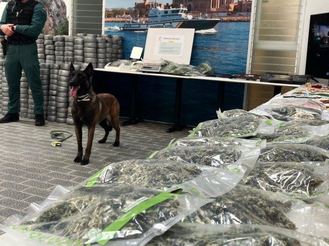 Una unidad canina de la Guardia Civil junto a droga, dinero y objetos expuestos por la Guardia Civil, procedentes de la operación 'Jaque Mate'.