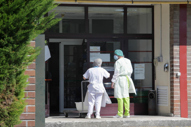 Archivo - Dos trabajadores conversan en la puerta de una residencia en la época de la pandemia.