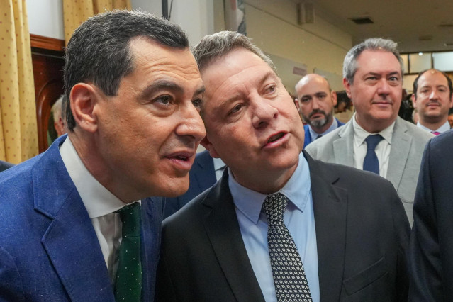 El presidente de la Junta de Andalucía, Juanma Moreno, y el de Castilla-La Mancha, Emiliano García-Page, en una imagen de 13 de abril en la exposición '40 años de la Casa de Castilla-La Mancha'. De fondo, el secretario general del PSOE-A, Juan Espadas.
