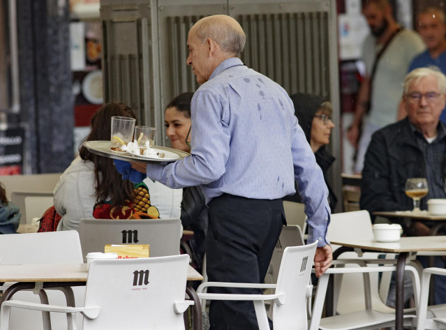 Archivo - Un camarero porta una bandeja en una terraza de un bar de Madrid