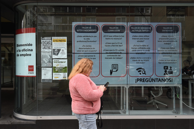 Archivo - Una mujer pasando ante una oficina de empleo de la Comunidad de Madrid