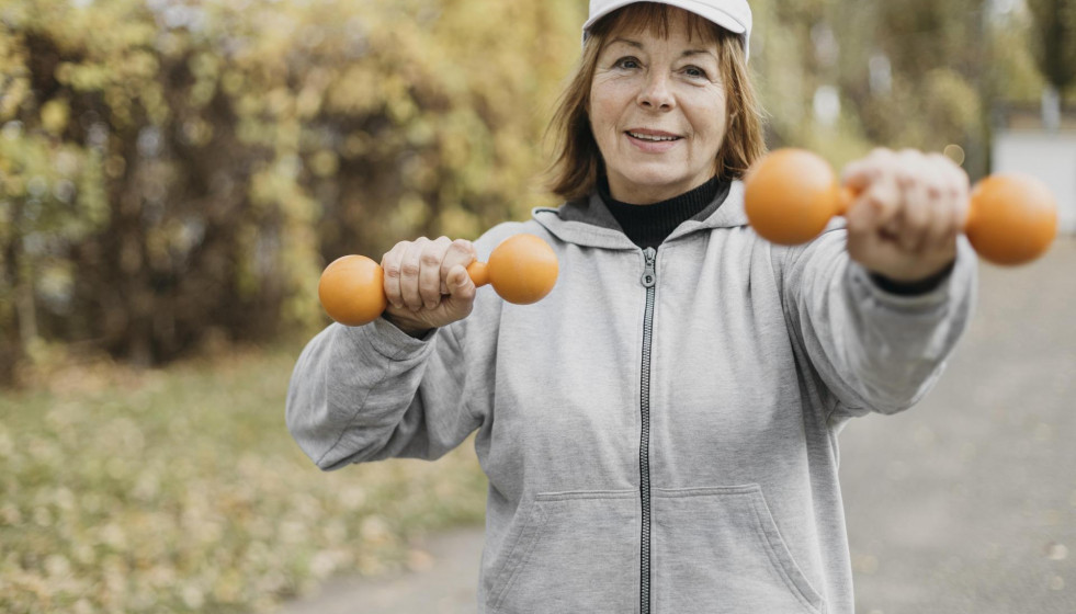Smiley elderly woman working out with weights