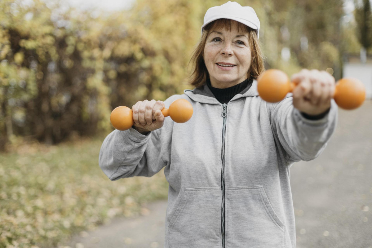 Smiley elderly woman working out with weights