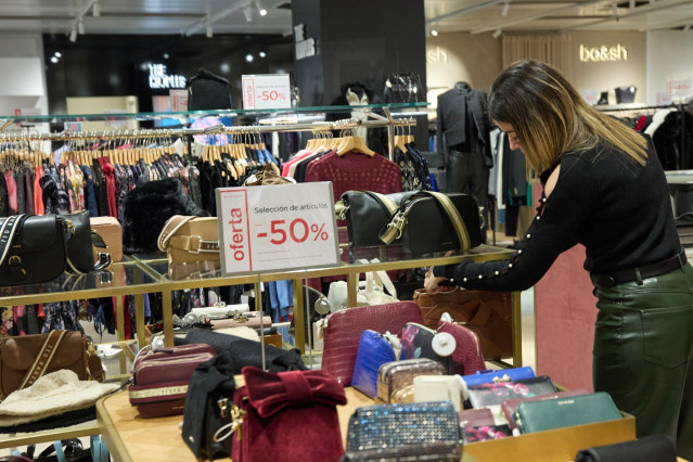 Archivo - Una mujer observa un bolso, en los primeros minutos de rebajas