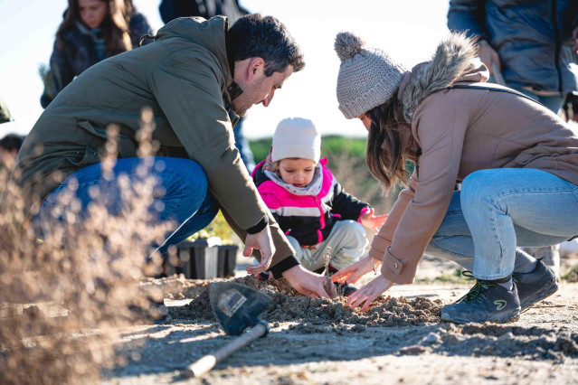 Una familia de Aedas Homes plantando un árbol en la parcela de Cobeña