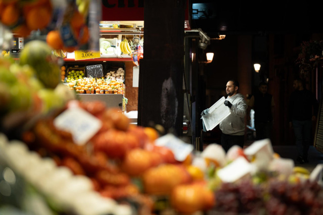 Archivo - Un comerciante revisa sus productos expuestos
