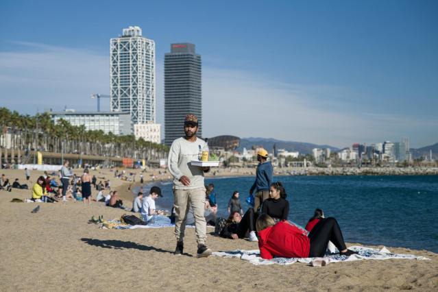 Archivo - Un camarero lleva bebidas a clientes en una playa