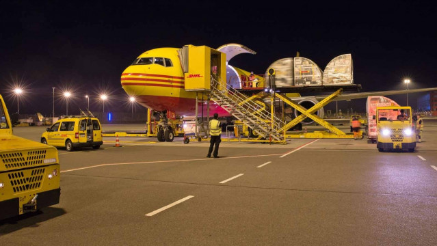 Archivo - Un avión de transporte de mercancías de la compañía DHL, con operarios realizando labores de carga, en una imagen de archivo.