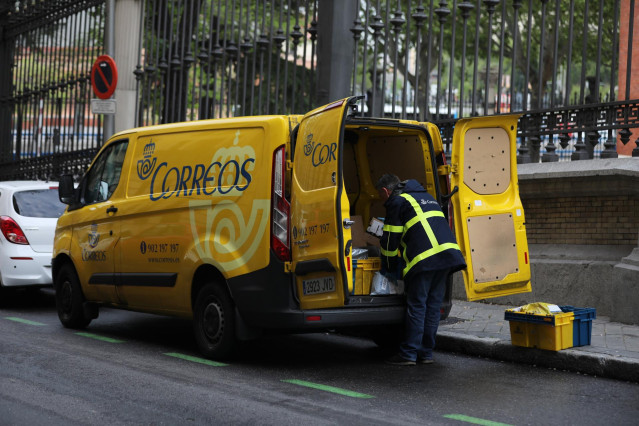 Archivo - Un trabajador de Correos extrae de su furgoneta paquetes y cartas, en Madrid (España), a 14 de abril de 2020.