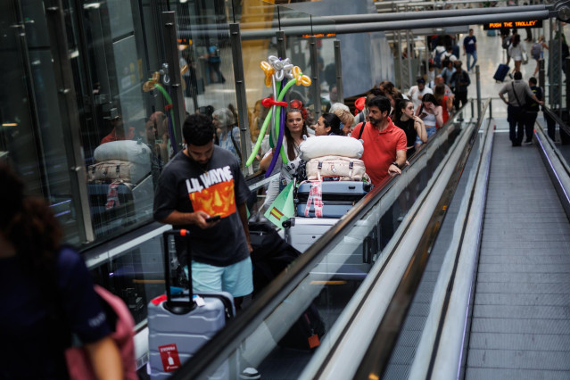 Archivo - Varias personas en una escalera mecánica de la terminal T4 del aeropuerto Adolfo Suárez-Madrid Barajas, a 30 de junio de 2023, en Madrid (España).