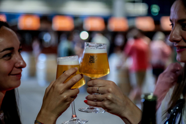 Archivo - Dos mujeres catan unas cervezas rubias en copa de cristal