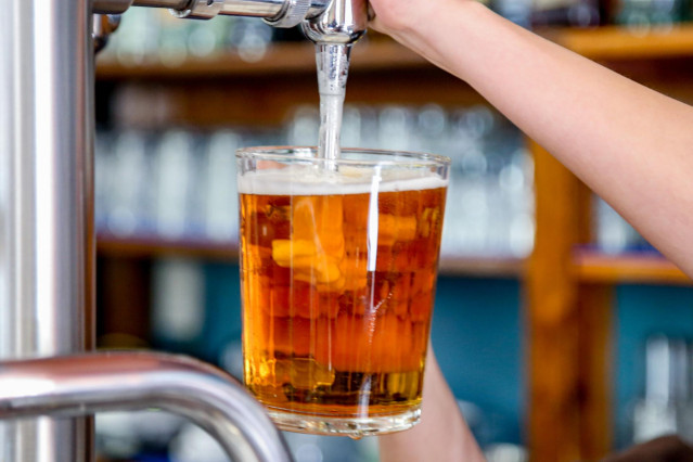 Archivo - Un camarero tira una cerveza en un bar.