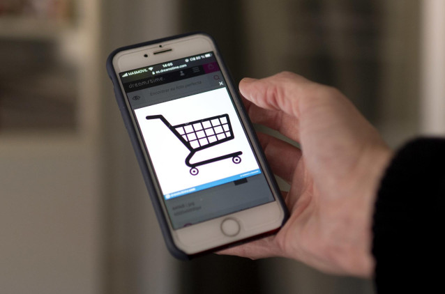Archivo - Una persona compra a través de su teléfono móvil