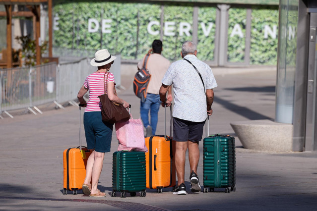 Dos señores mayores esperan con sus maletas en una calle de Madrid, a 28 de agosto de 2024, en Madrid (España). L