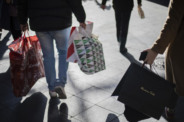 Archivo - Varias personas con bolsas de la compra en una calle céntrica