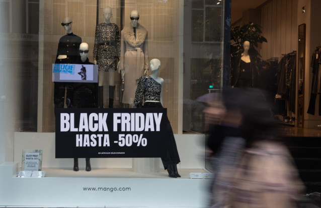 Archivo - Varias personas pasan por delante de los comercios que anuncian los descuentos del Black Friday, a 24 de noviembre de 2022, en Madrid (España).