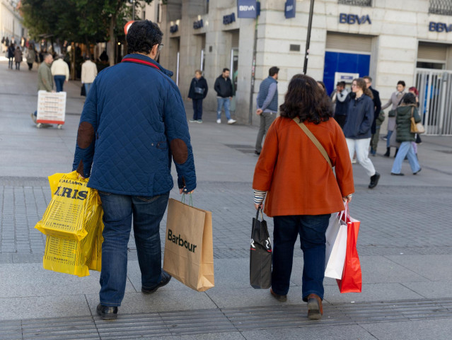 Archivo - Dos personas llevan varias bolsas de compra