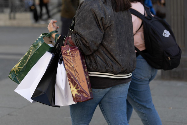 Archivo - Una persona lleva varias bolsas de compra