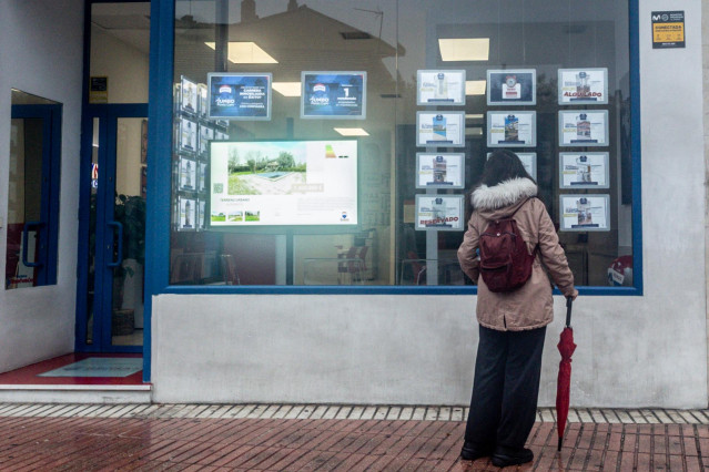 Archivo - Una mujer observa las ofertas de una inmobiliaria