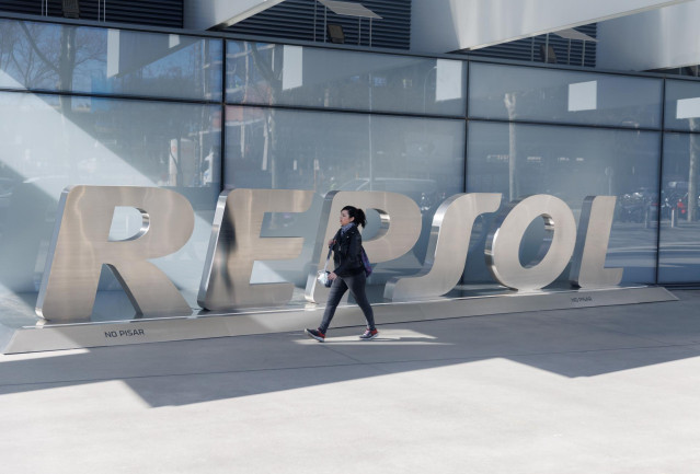 Archivo - Una mujer camina frente a las letras Repsol en su sede de Madrid
