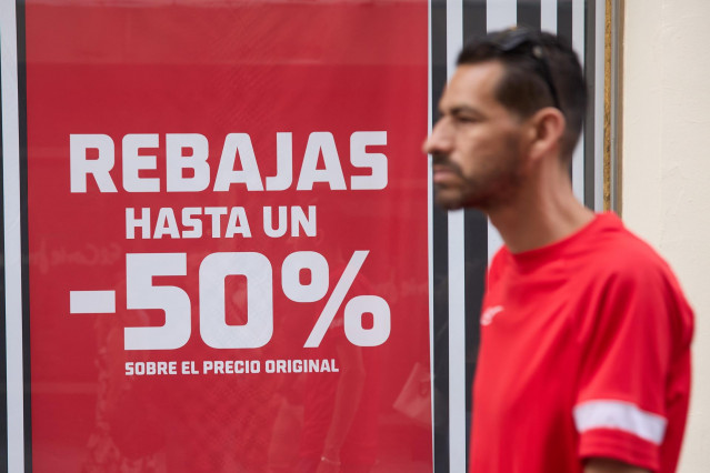 Archivo - Una persona pasa delante de un escaparate durante el comienzo de las rebajas