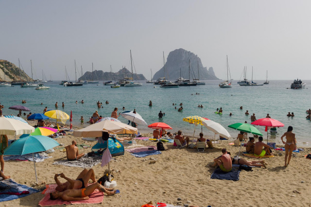 Archivo - Varias personas en la playa de Cala d'Hort, a 11 de julio de 2023, en Ibiza, Islas Baleares (España). Los datos de la Federación Empresarial Hotelera de las Pitiusas indican que todas las zonas turísticas de la isla de Ibiza registraron grandes