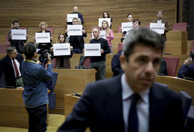 El 'president' Carlos Mazón, ante carteles de Compromís pidiendo su dimisión en Les Corts
