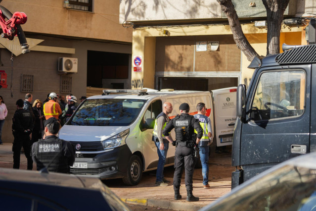 Varios agentes de la Guardia Civil y de la Policía junto a un vehículo funerario tras el derrumbe de una escalera, a 18 de enero de 2025, en Benetússer