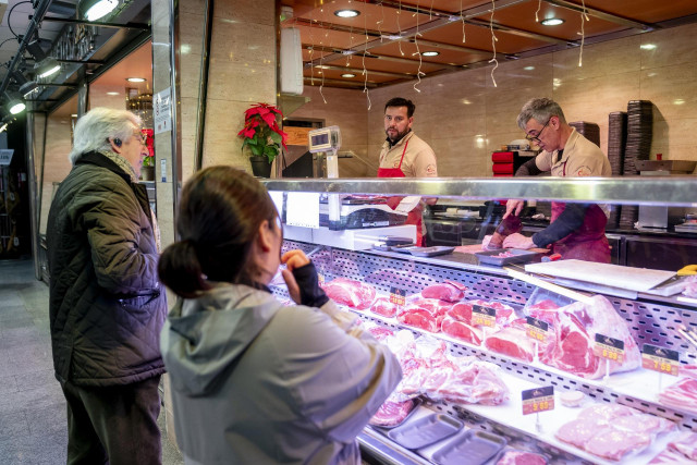 Varias personas hacen compras en un mercado.