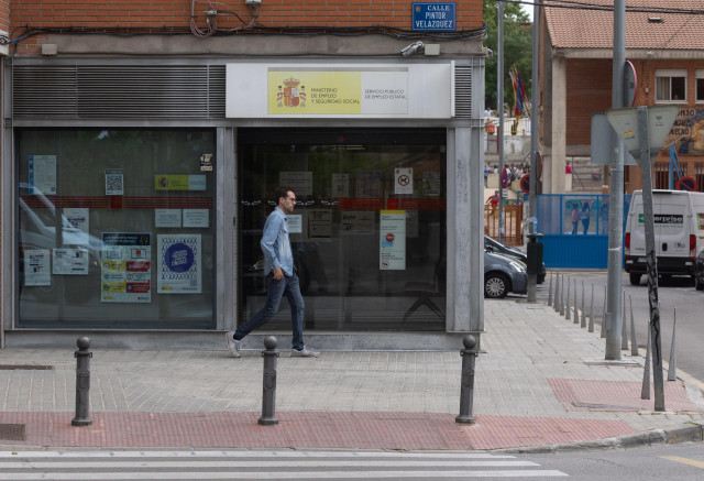 Archivo - Una persona camina al lado de una oficina de empleo