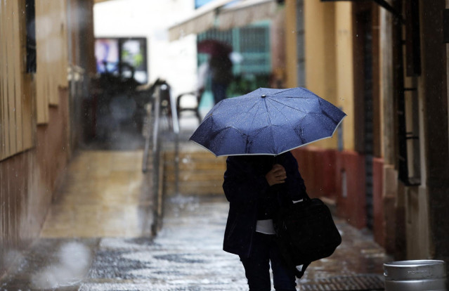 Una persona se protege de la lluvia en Málaga. A 13 de marzo de 2025, en Málaga (Andalucía, España)