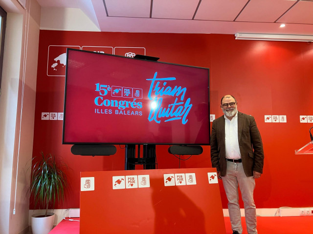 El secretario de organización del PSIB, Cosme Bonet, junto al nuevo logo y lema del partido de cara a su 15º Congreso.