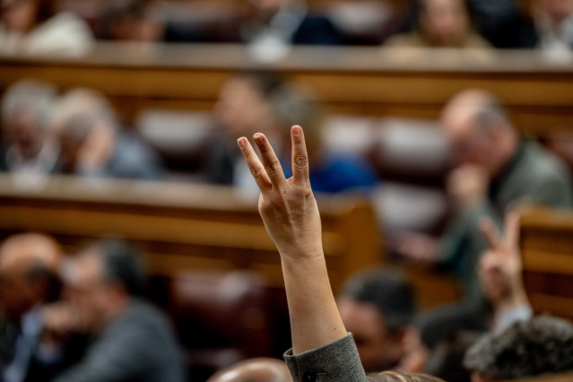 Archivo - Una persona indica el sentido de voto  durante una sesión plenaria del Congreso